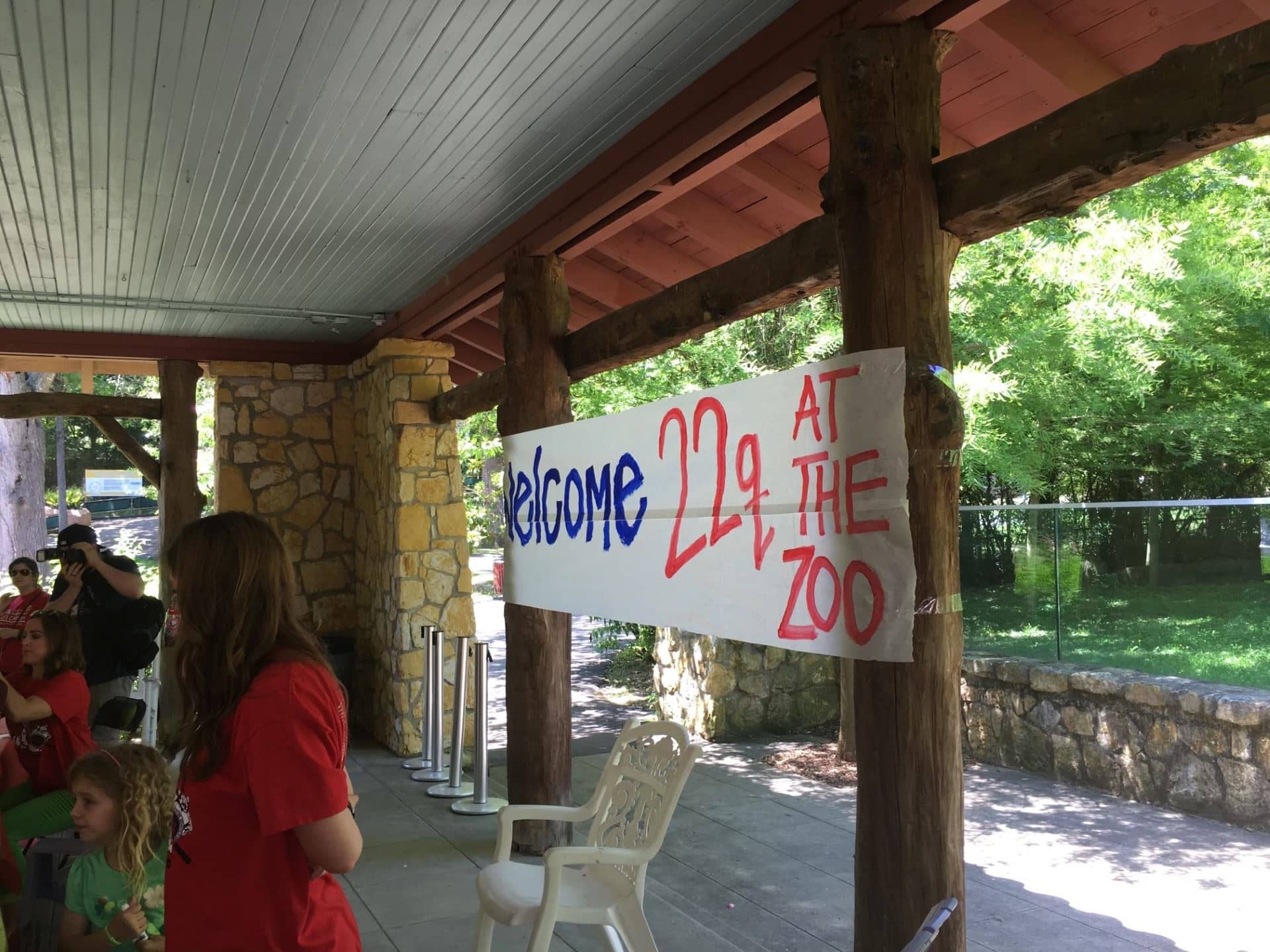 Sign that reads "22q at the Zoo" with people standing near. 